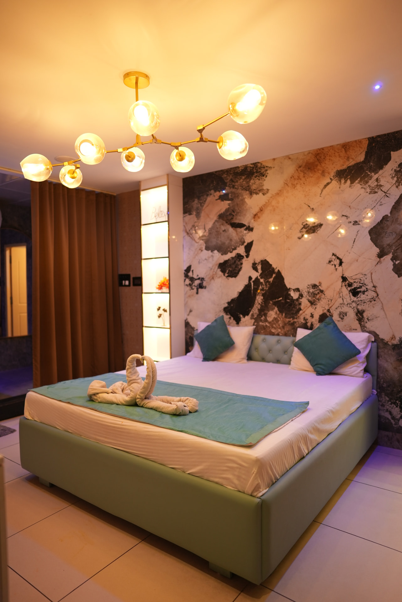 Luxury couples spa suite with marble wall, gold chandelier and turndown setup